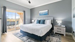 A bedroom with a bed, a ceiling fan, a nightstand, a lamp, and a view through a glass door. - Golf Course View Condo w/ Pool Access, Near Disney (Reunion)