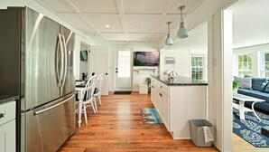 A spacious kitchen with a wooden floor, white cabinetry, and a stainless steel refrigerator. - Bayfront Villa:  Dock, Walk to Beach and Bridge Street (Bradenton Beach)
