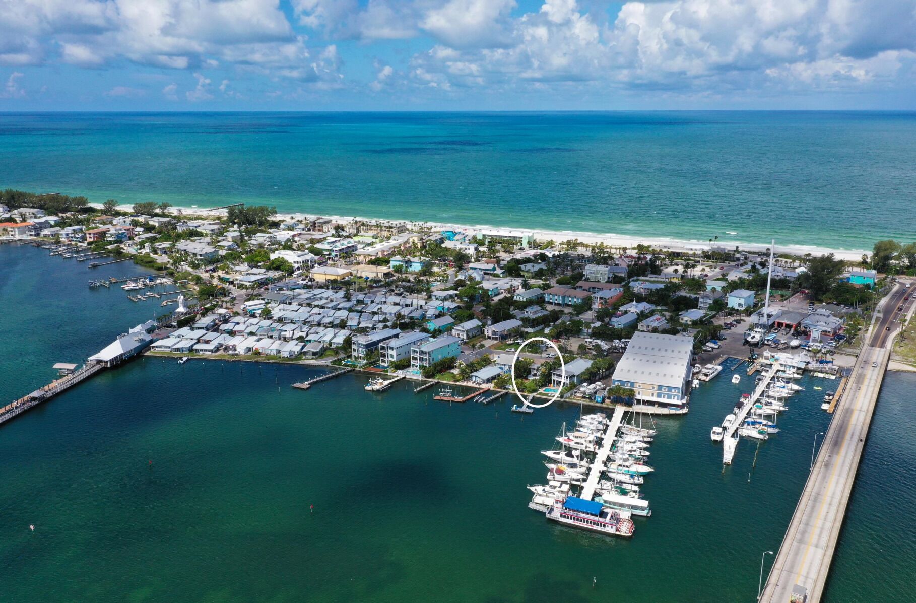 An aerial view of a coastal town with a marina, houses, and a beach.