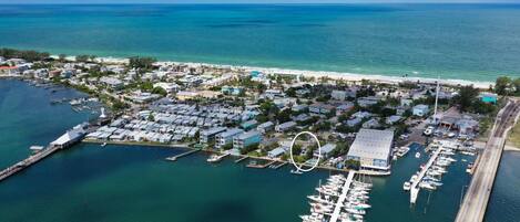 An aerial view of a coastal town with a marina, houses, and a beach.