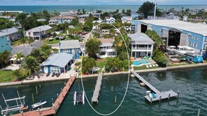 An aerial view of a coastal residential area with houses, a marina, and a dock. - Bayfront Villa:  Dock, Walk to Beach and Bridge Street (Bradenton Beach)