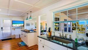 A modern kitchen with a large island, a built-in oven, and a window with a view of palm trees. - Bayfront Villa:  Dock, Walk to Beach and Bridge Street (Bradenton Beach)