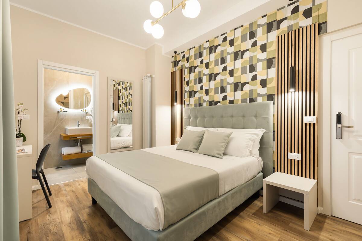 Un dormitorio moderno con una cama grande, mesitas de noche, un tocador con espejo y piso de madera.