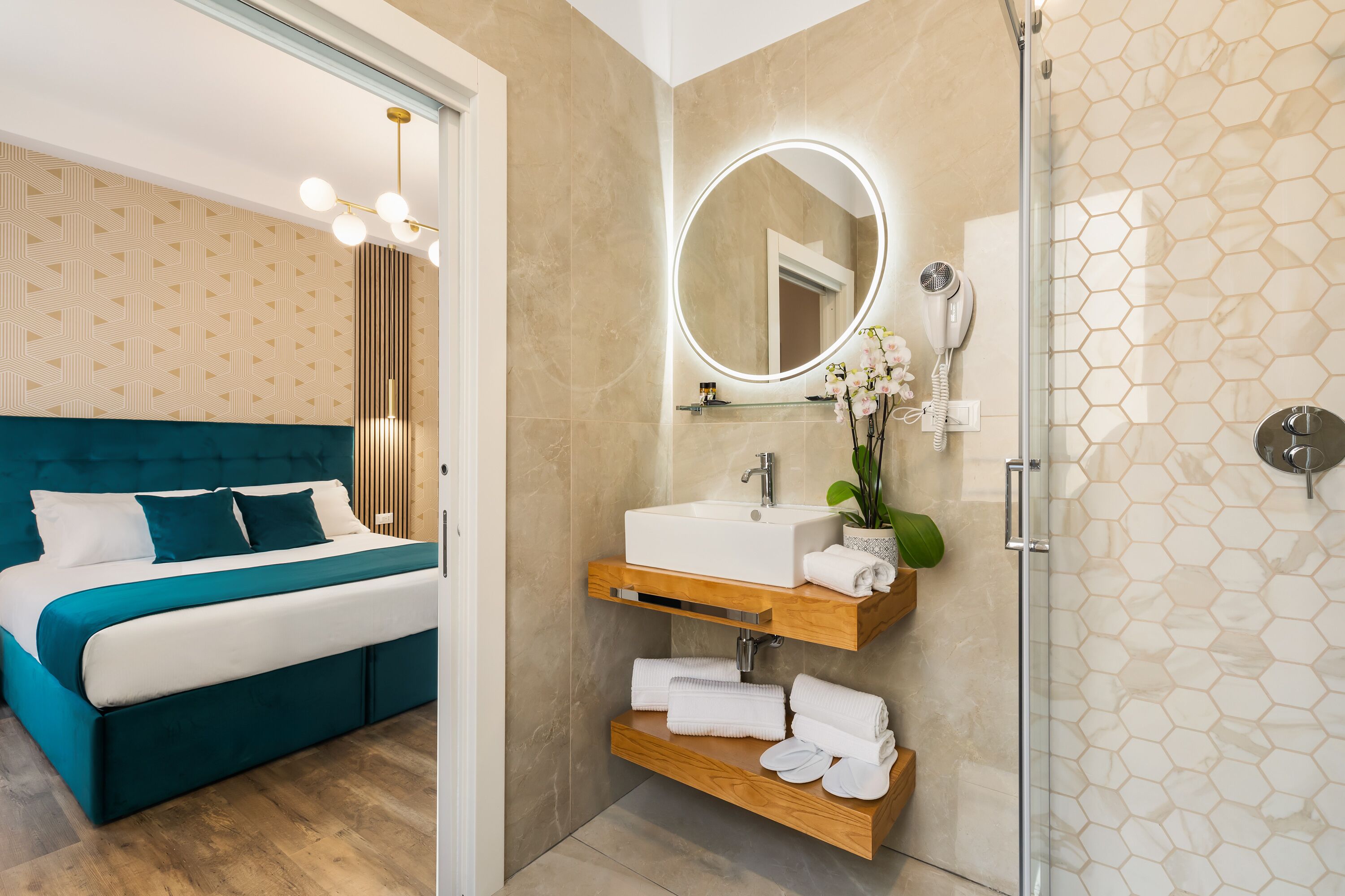 Een moderne slaapkamer met een bed, een badkamer met wastafel, spiegel en douche.