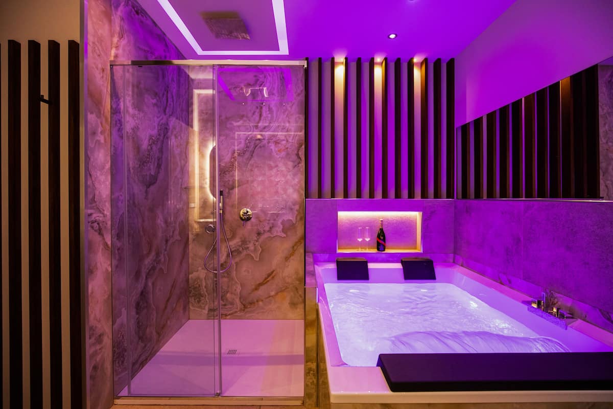Un baño moderno con ducha de vidrio, una bañera grande y un tocador con encimera de mármol.