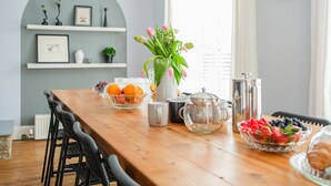 Ein Esstisch mit Obstschalen, einer Blumenvase und Geschirr.