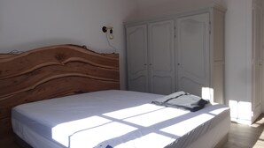 A bedroom with a wooden headboard, a white bed, and a white wardrobe. - Au Calme, Centre La Tranche-sur-mer, 200m Commerces et Rues Animées, 300m Plage (La Tranche-sur-Mer)