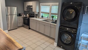 Une cuisine moderne équipée d’appareils électroménagers en acier inoxydable, d’un four encastré et d’un grand lave-linge noir.