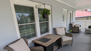 Une véranda couverte, aménagée avec des meubles en osier, une table et des plantes en pot.