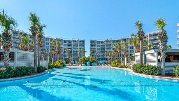 A swimming pool surrounded by palm trees and modern buildings.