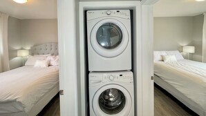 Une chambre d’hôtel équipée d’un lave-linge et d’un sèche-linge intégrés, de deux lits avec du linge de lit blanc et de lampes de chevet.