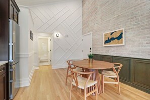 Een keuken met een houten eettafel en stoelen, een koelkast en een bakstenen muur met een kaart als kunstwerk.