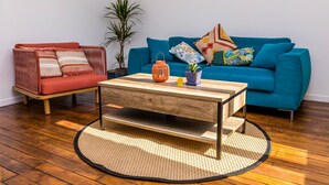 A living room with a red sofa, a blue sofa, a wooden coffee table, and a potted plant. - Maison Calme et Confortable à 10 Minutes de Paris (Alfortville)