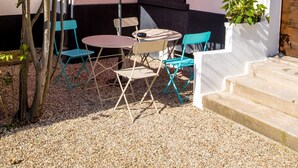 An outdoor seating area with a red umbrella, a small table, and blue chairs. - Maison Calme et Confortable à 10 Minutes de Paris (Alfortville)