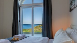 Une chambre d’hôtel avec un lit, une vue sur la mer et une fenêtre avec des rideaux.