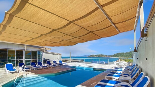 A pool area with sun loungers and a large canopy. - 1 Bright Point Apartment 1407 (Nelly Bay)