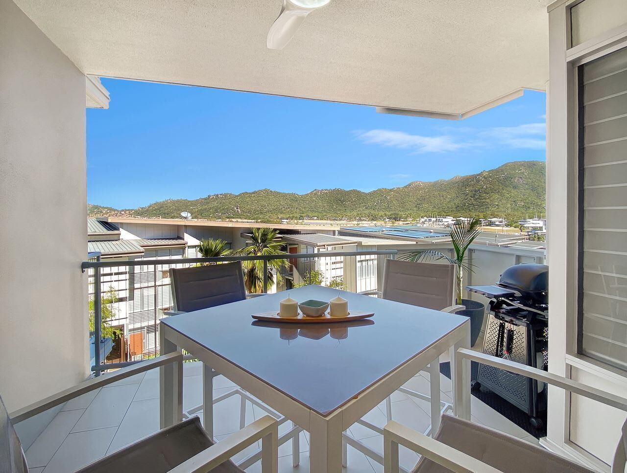 Un balcon équipé d’une table, de chaises, d’un barbecue et offrant une vue sur un paysage montagneux.