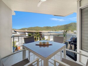 Un balcon équipé d’une table, de chaises, d’un barbecue et offrant une vue sur un paysage montagneux.