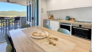 A modern kitchen with a dining area, a view of the outdoors, and a ceiling fan. - 1 Bright Point Apartment 1407 (Nelly Bay)