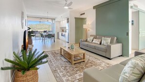 A modern living room with a sofa, coffee table, and a large plant. - 1 Bright Point Apartment 1407 (Nelly Bay)