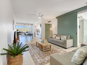 A modern living room with a sofa, coffee table, and a large plant. - 1 Bright Point Apartment 1407 (Nelly Bay)