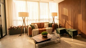 Ein modernes Wohnzimmer mit einer Sofagarnitur, zwei Stehlampen, einem Couchtisch und einer Wand aus Holz.