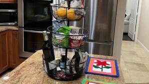 A kitchen with wooden cabinets, a stainless steel refrigerator, and a three-tiered basket holding various items. - Maison Duffailly (Pompano Beach)
