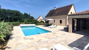 Une piscine dotée de chaises longues et d’un patio couvert.