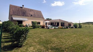 Une maison à deux étages dotée d’un patio couvert, d’une piscine et d’une pelouse bien entretenue.