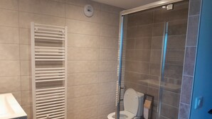 Ein modernes Badezimmer mit einer Duschkabine, einer weißen Toilette und einem Handtuchhalter.