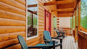 A wooden cabin with a porch, two Adirondack chairs, and a red door. - Beary Cozy Den (Gatlinburg)
