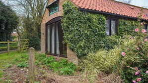 A rustic building with a red-tiled roof, a sign indicating 'Open Farm', and a wooden gate. - UK46717 - The Orchard (Plumstead Green, near Holt)