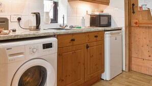 A compact kitchen with a washing machine, a microwave, and a dishwasher. - UK46717 - The Orchard (Plumstead Green, near Holt)