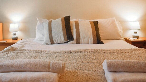 A neatly made bed with striped pillows, a fluffy beige blanket, and two folded towels on the bed. - UK46717 - The Orchard (Plumstead Green, near Holt)