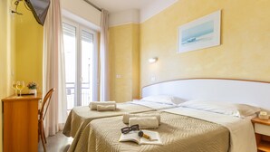 A hotel room with two beds, a desk, and a chair. - HOTEL NAICA (Rimini)