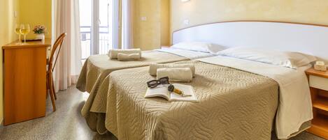 A hotel room with two beds, a desk, and a chair.