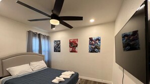 A bedroom with a bed, ceiling fan, artwork on the wall, and a TV. - Open concept modern home: about 20 minutes or less to Disney,Malls, Beaches, etc (Santa Ana)