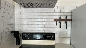 A kitchen with white tiled backsplash, a stainless steel range hood, a black stove, and a knife rack. - Open concept modern home: about 20 minutes or less to Disney,Malls, Beaches, etc (Santa Ana)