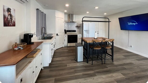 A compact kitchen with a dining area, a TV mounted on the wall, and a small refrigerator. - Open concept modern home: about 20 minutes or less to Disney,Malls, Beaches, etc (Santa Ana)