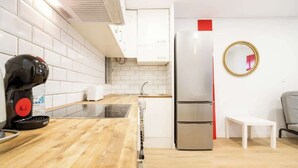 A compact kitchen with white cabinets, a stainless steel refrigerator, a coffee machine, and a small white table. - Old Town • Santes Creus - Unik Vacation (Tarragona)