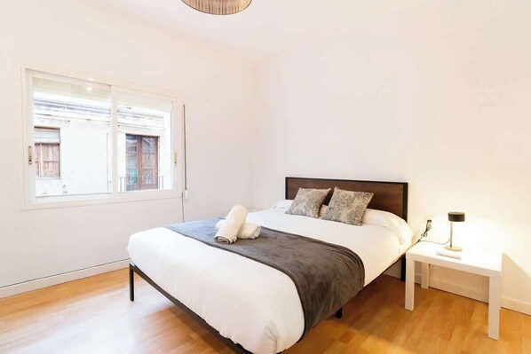 A bedroom with a bed, bedside table, and a window.