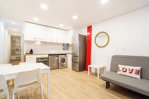 A compact living space with a kitchenette, a dining area, and a seating area with a sofa and a small table.