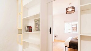 A modern bedroom with a bed, a hanging light fixture, and a view of a cityscape through a window. - Old Town • Santes Creus - Unik Vacation (Tarragona)