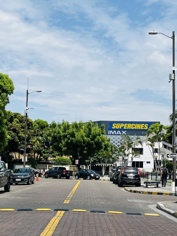 Eine Straße mit parkenden Autos, einem Supercines IMAX Schild und einer Fußgängerampel.