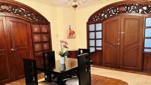 Un comedor con una mesa y sillas, una planta en maceta y dos grandes puertas de madera.