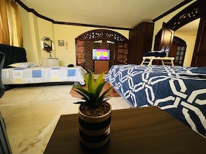 A hotel room with two beds, a TV, a wooden wardrobe, and a potted plant. - Mega Suite en PB al lado del San Marino (Guayaquil)