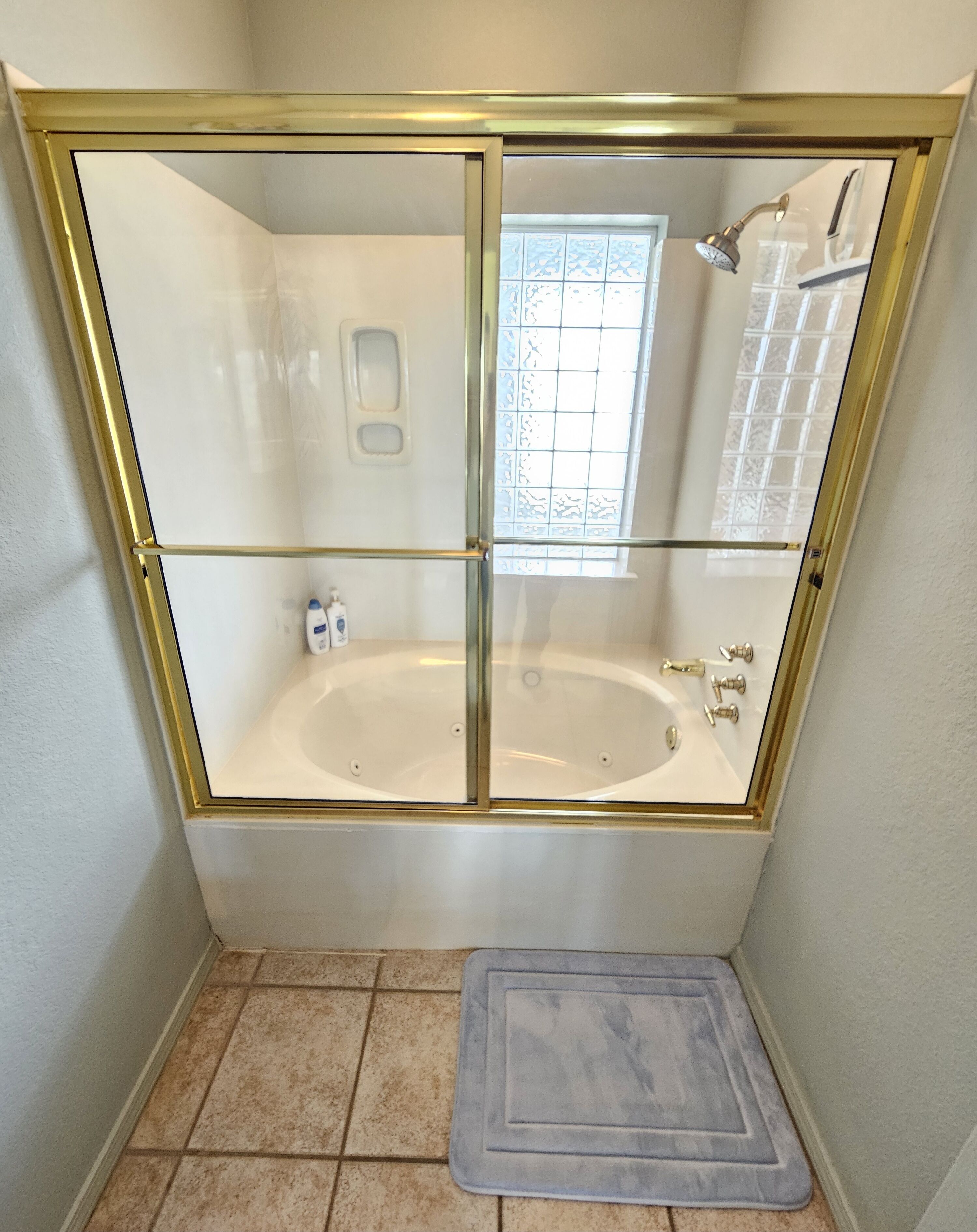 Une salle de bain avec une douche à parois de verre, une baignoire et une petite fenêtre.