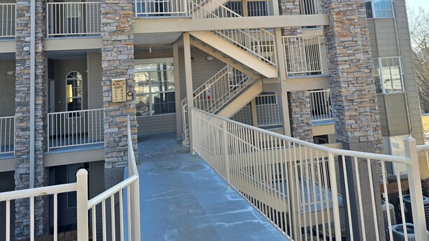 A multi-story building with a central staircase surrounded by balconies, stone pillars, and a gated entrance. - Captains Quarters Walk-in Suite at the Legacy at Thousand Hills! Great Rates! (Branson)