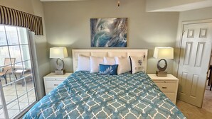 A bedroom with a bed, two bedside tables, a ceiling fan, a window with a view, and a door. - Captains Quarters Walk-in Suite at the Legacy at Thousand Hills! Great Rates! (Branson)