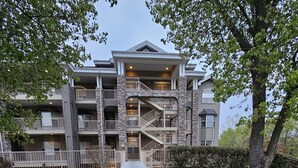 A multi-story building with a central staircase, surrounded by a well-maintained lawn and trees. - Captains Quarters Walk-in Suite at the Legacy at Thousand Hills! Great Rates! (Branson)